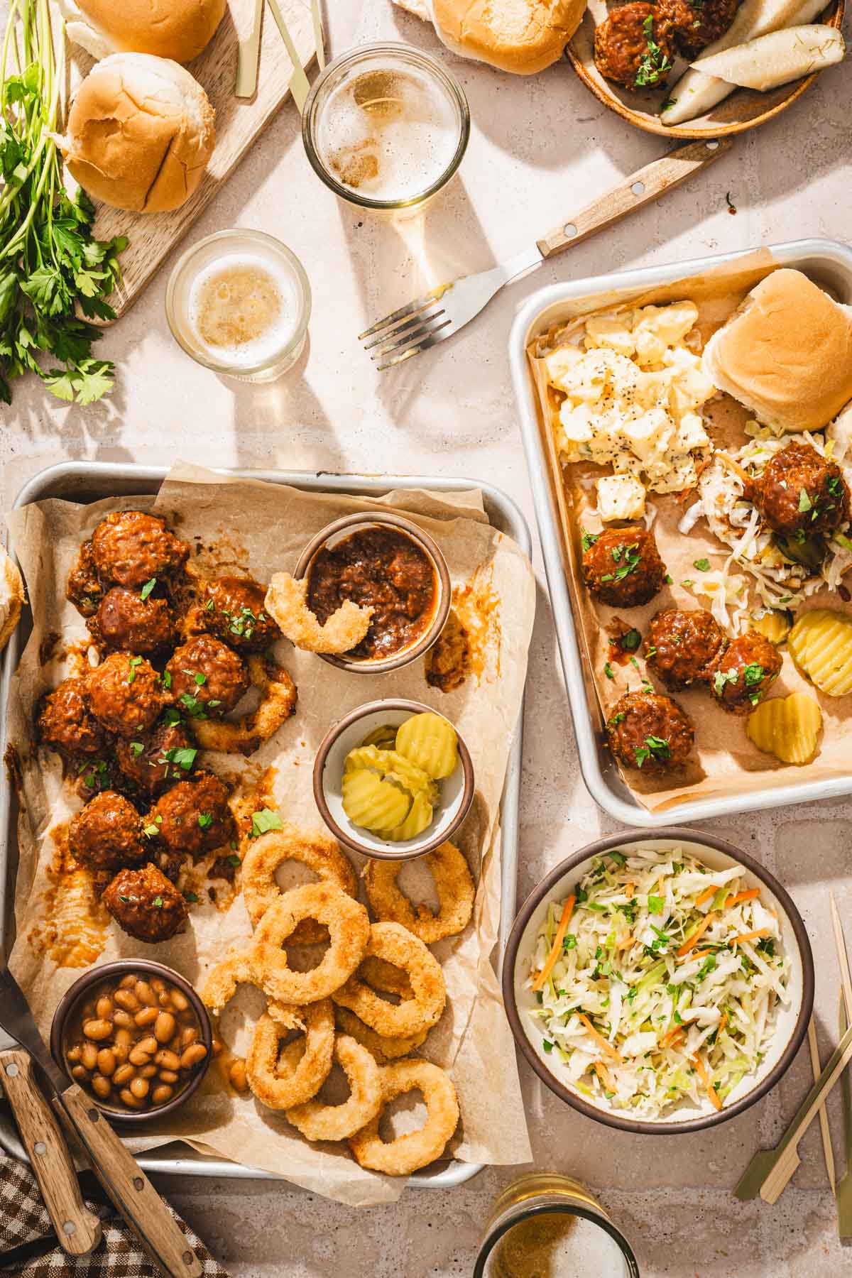 various small sheet pans with meatballs, slaad, beans, onion rings