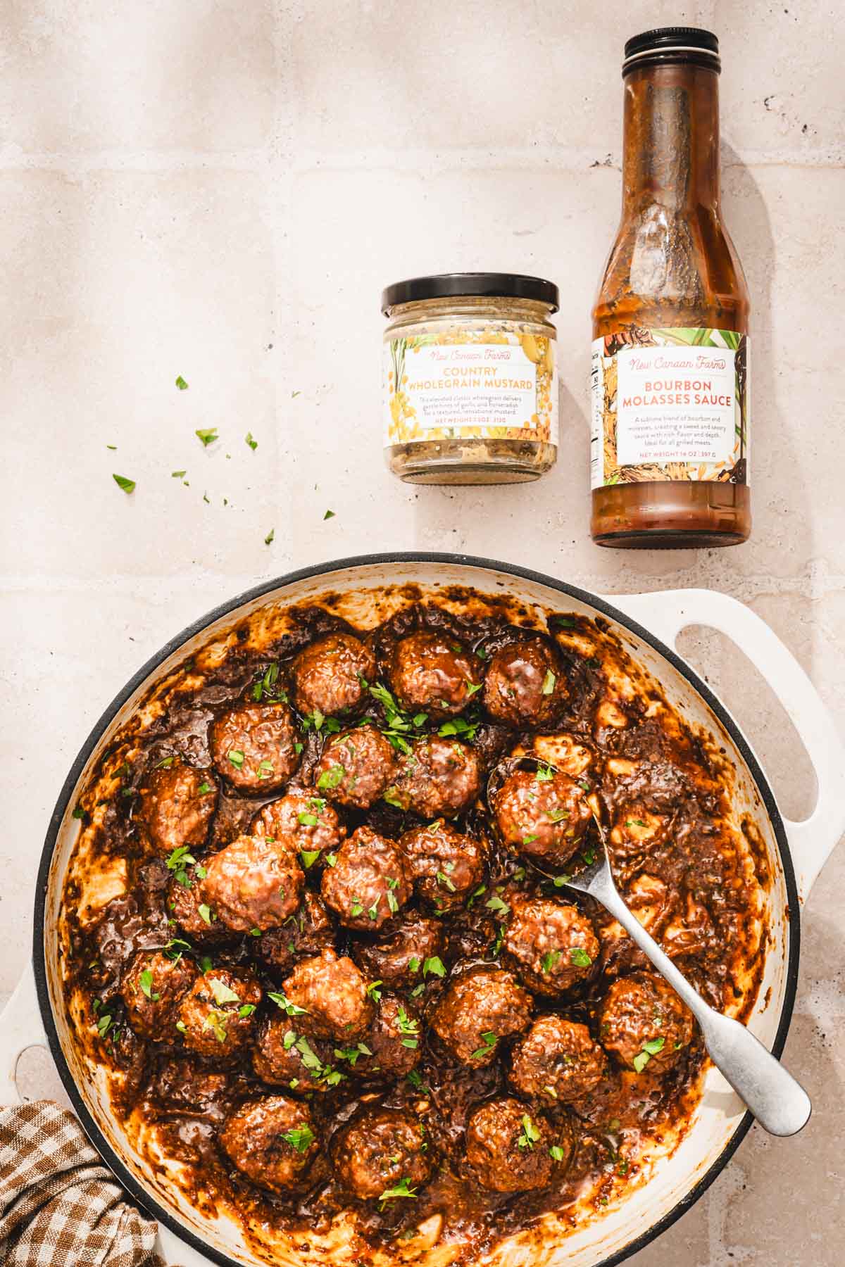 large skillet with browned meatballs in the b ourbon sauce and brand jars