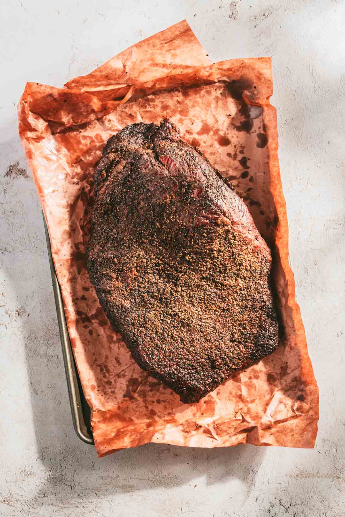 whole, smoked brisket on a butcher paper and baking sheet