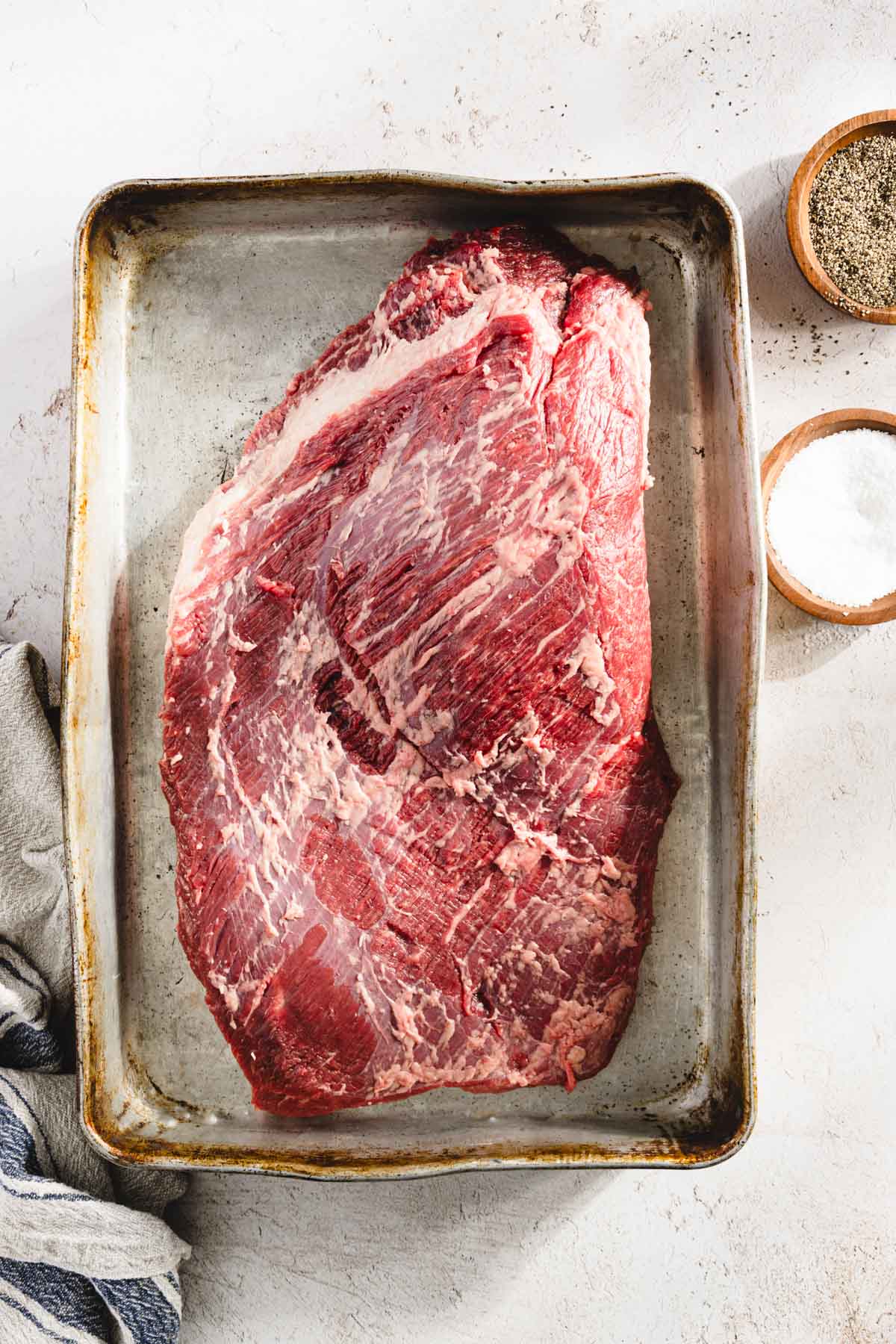 raw, trimmed brisket on a baking sheet, salt pepper