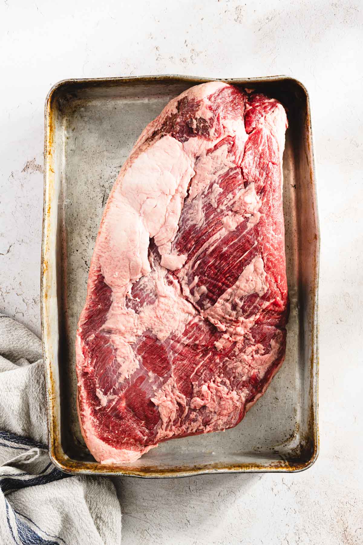 raw brisket on a baking sheet