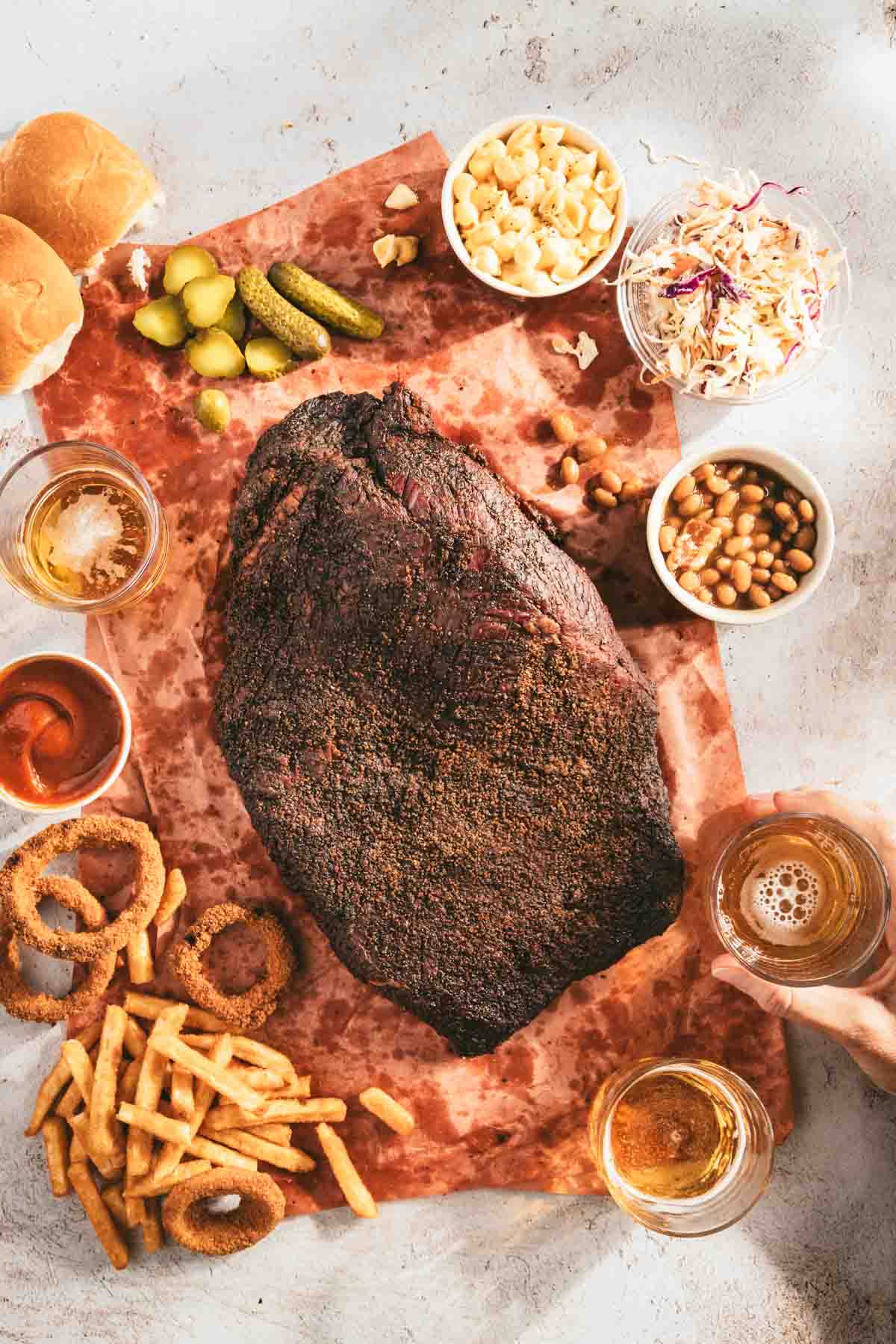 whole smoked brisket on a butcher paper, side dished around, glass with beer