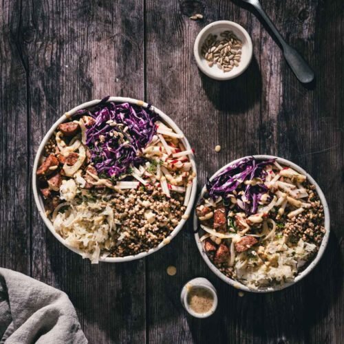 two buckwheat bowls with kielbasa, dish with sunflower seeds, dish with dressing