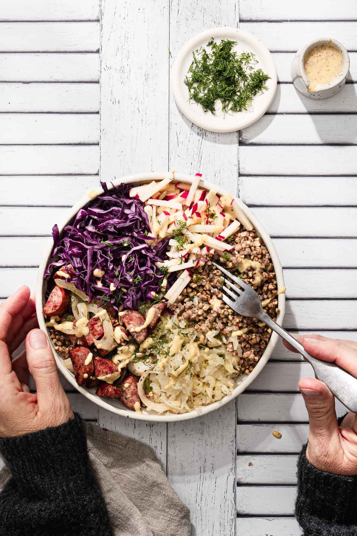 hands in frame holding fork over buckwheat bowl