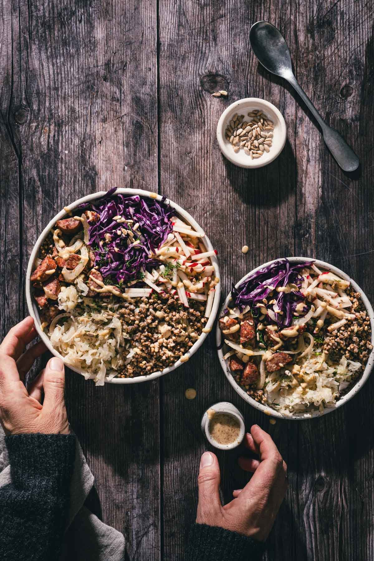 hands in frame holding fork over a buckwheat bowl, dish with dressing