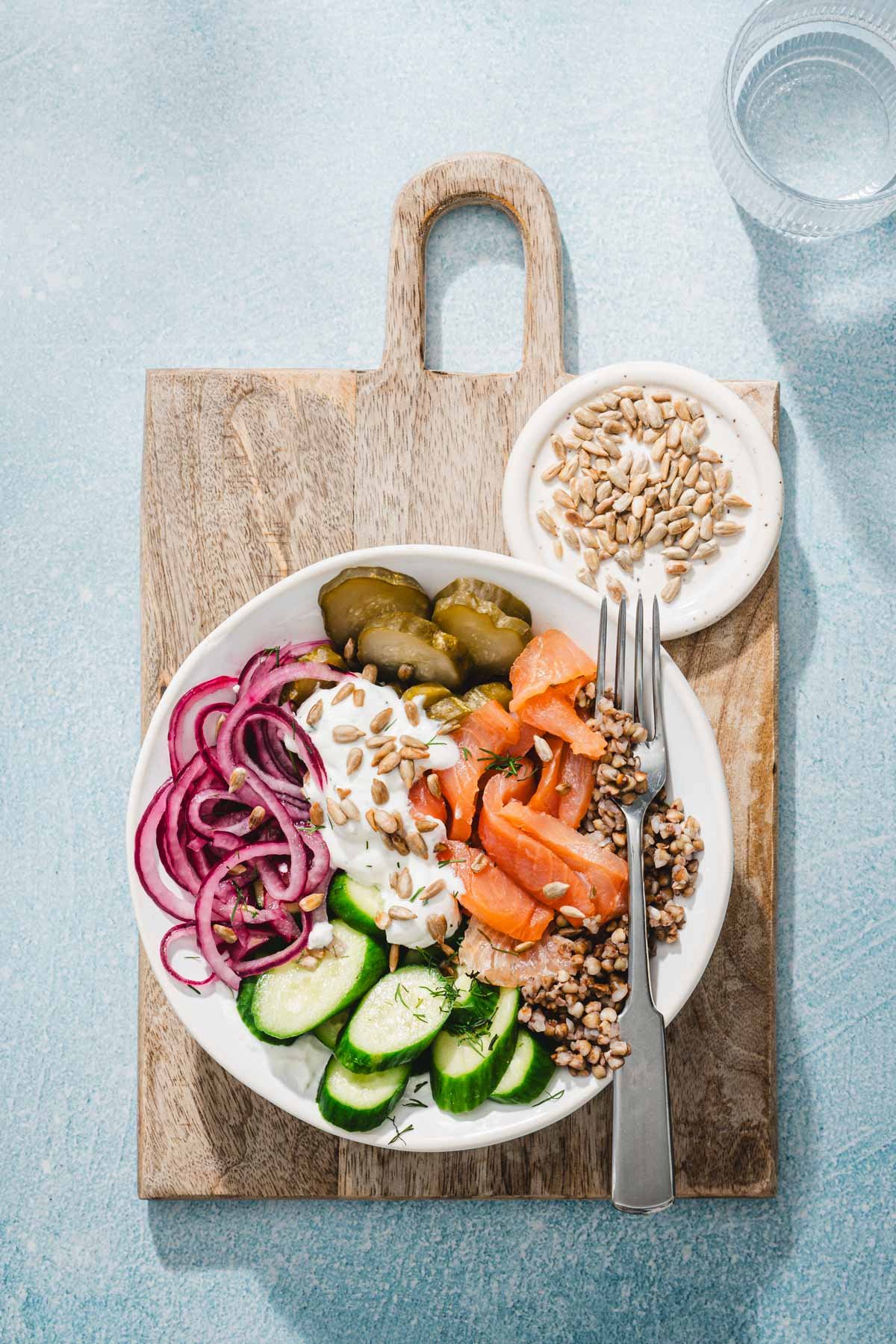 serving bowl with salmon and buckwheat on a serving borad