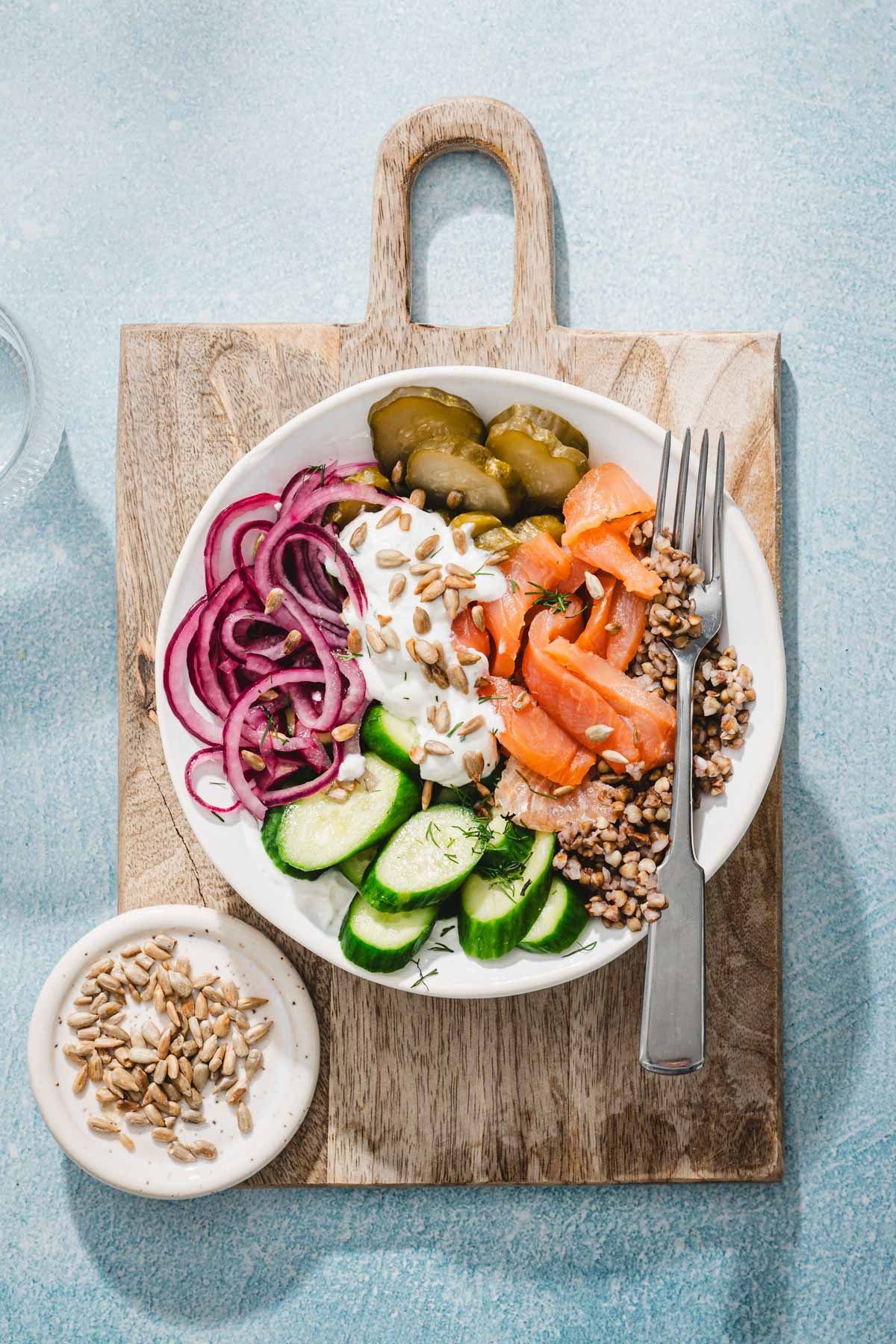 serving bowl with salmon and buckwheat on a serving wooden borad