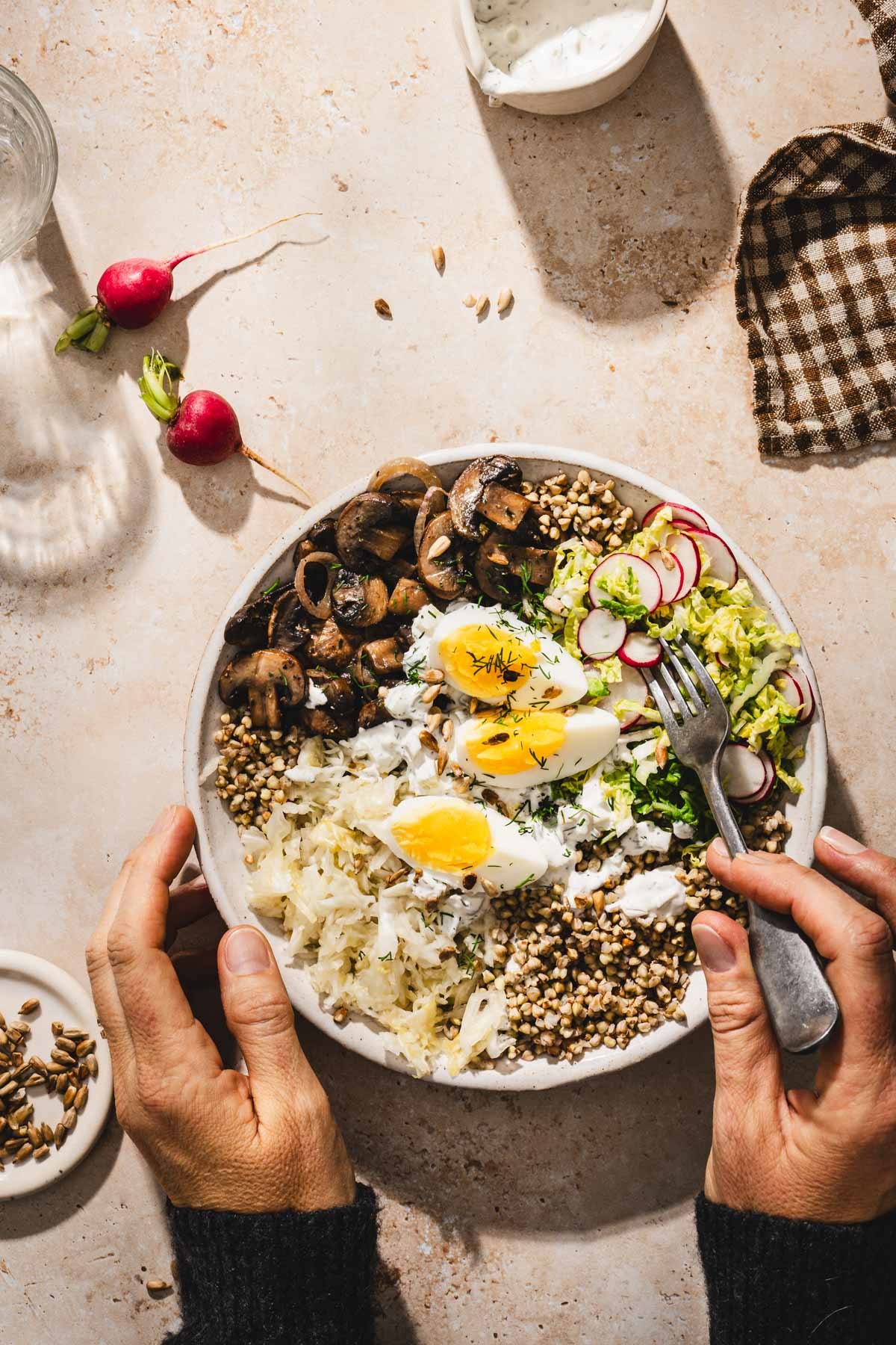 serving bowls with mushroom and buckwheat, hands in frame holding fork
