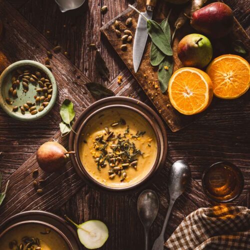 bowls with the soup, napkin, orange, pears