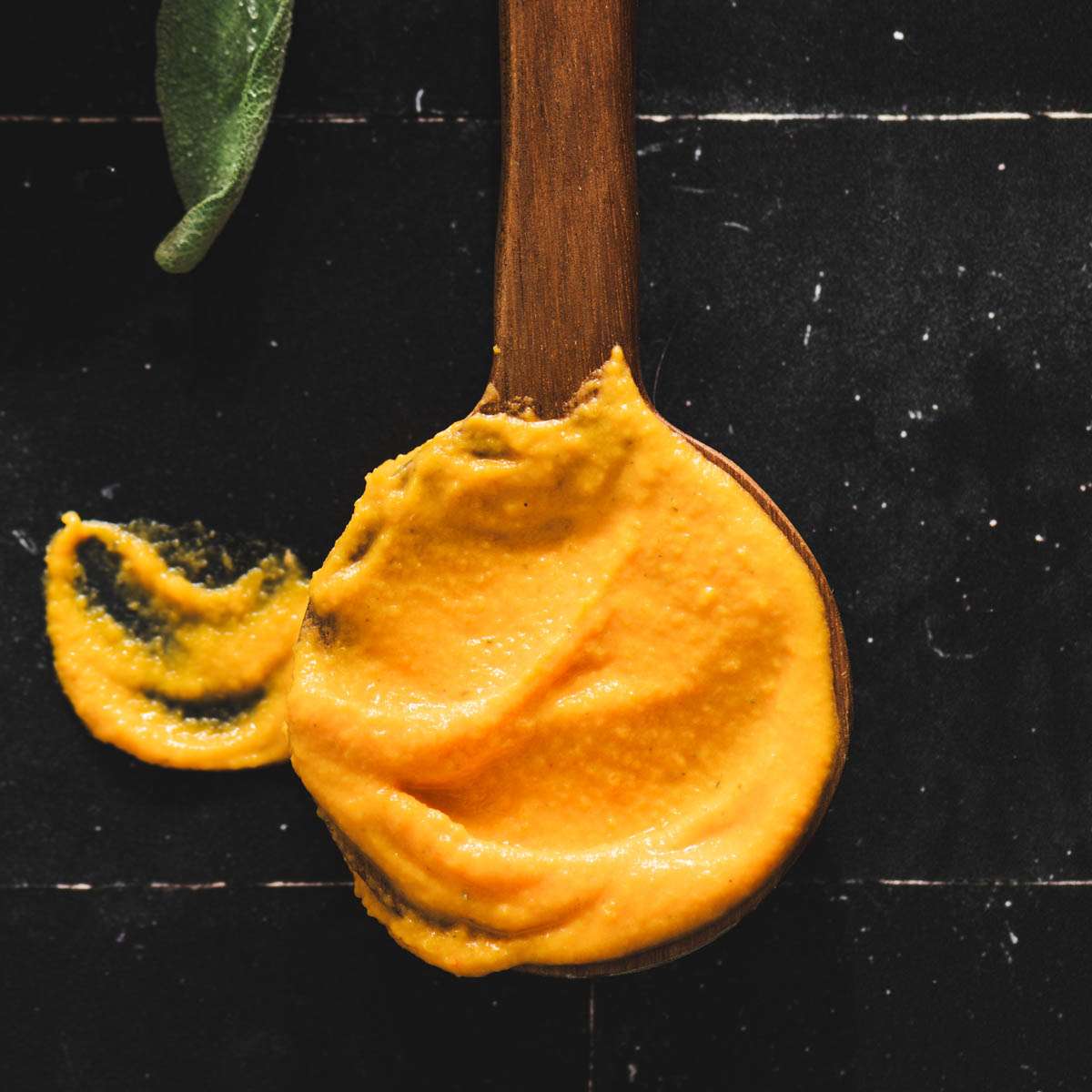 sauce close up on a wooden spoon, black background