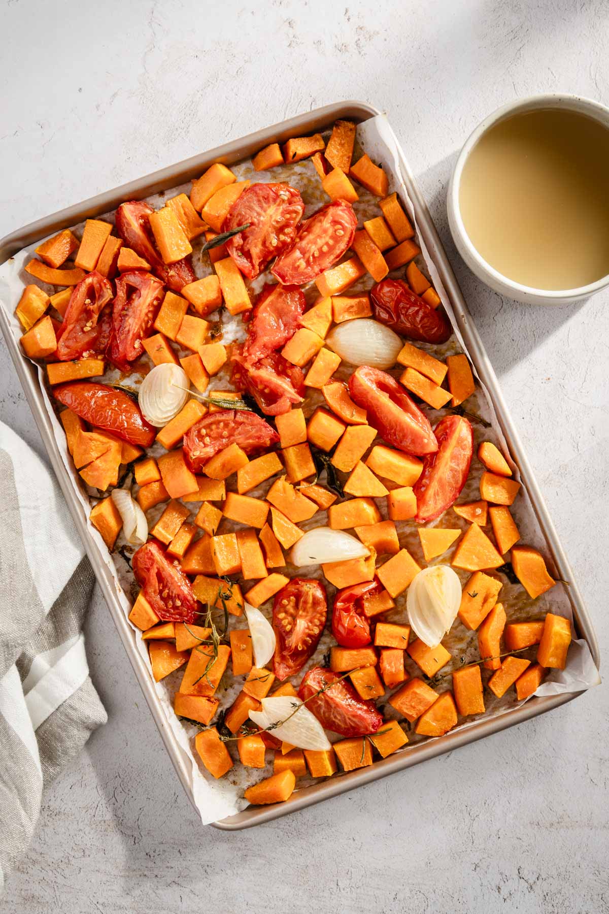 baking sheet with roasted veggies and small bowl with broth