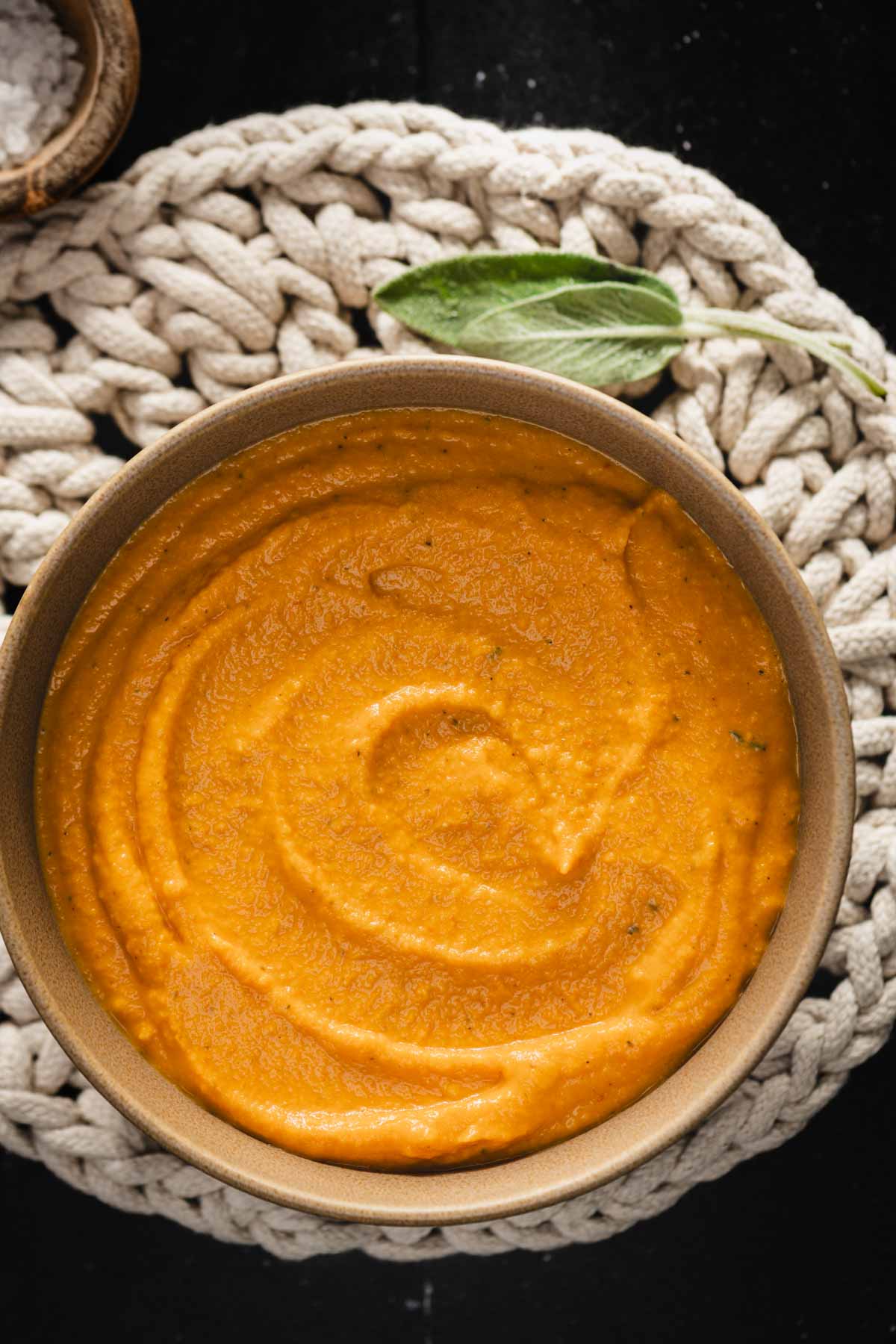 butternut sauce in a bowl, sage leaves and side dish with salt