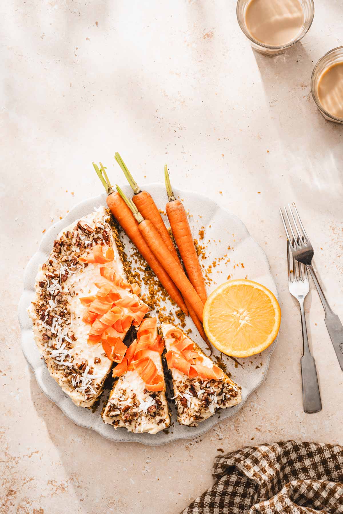 whol cake on a srving plate, fresh carrots, half of an orange