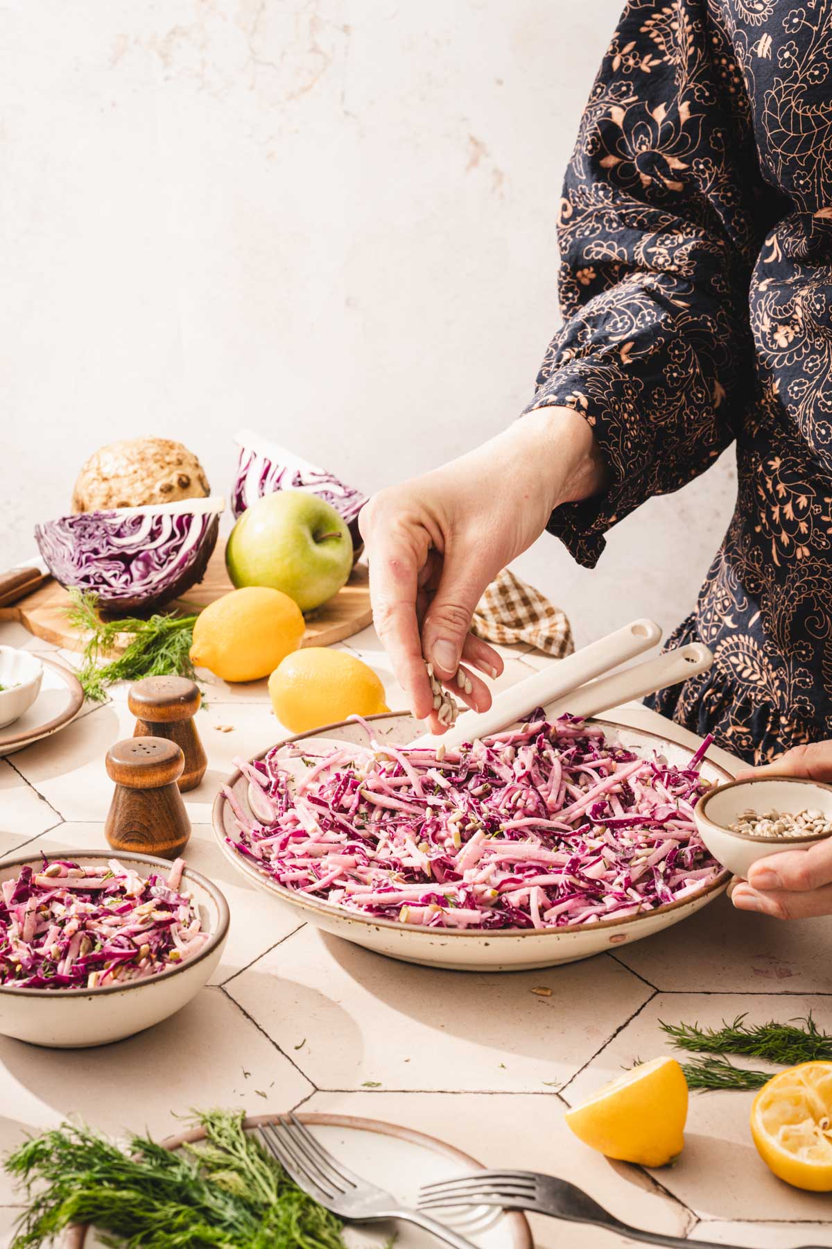 hands in frame holding sunflower seds ofver a bowl with salad