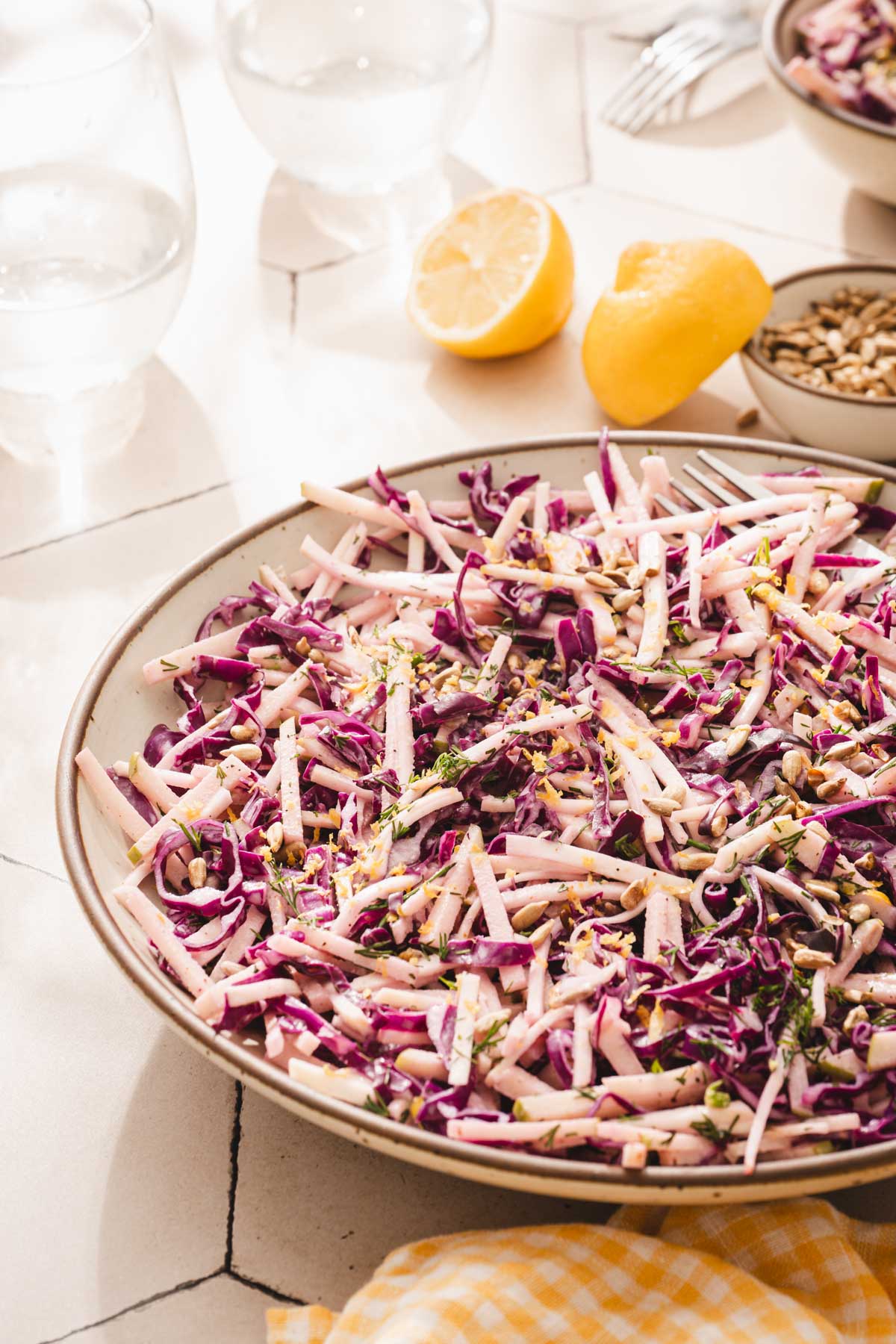 sid view of the bowl with salad, cut up lemon, glasss with water