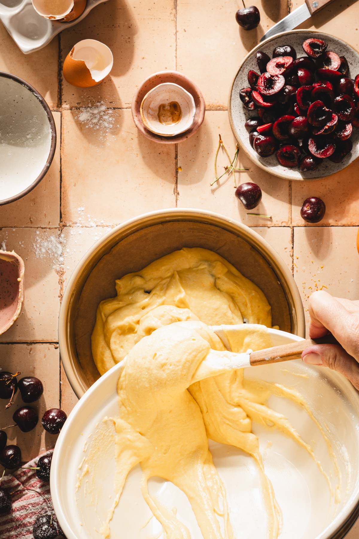 hands in frame pouring batter into prepared cake form