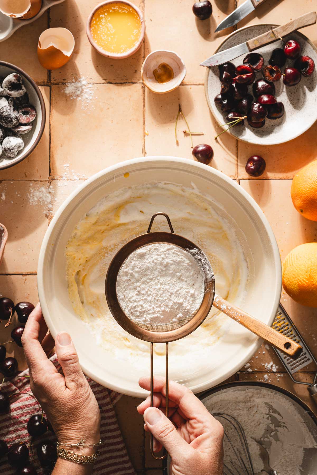 hands in frame holding strainer with flour