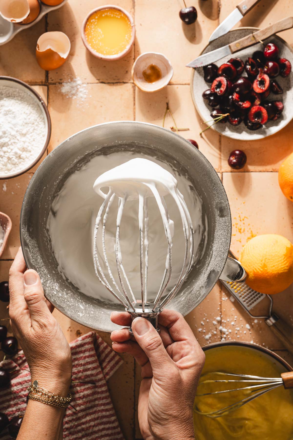 hands in frame holding whisk attachment with egg whites foam