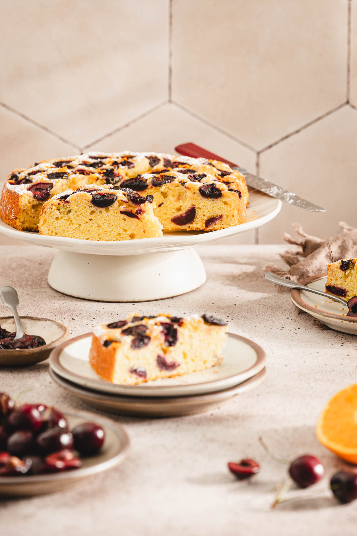 front view of a cake placed on a stand, few plates with cake slices