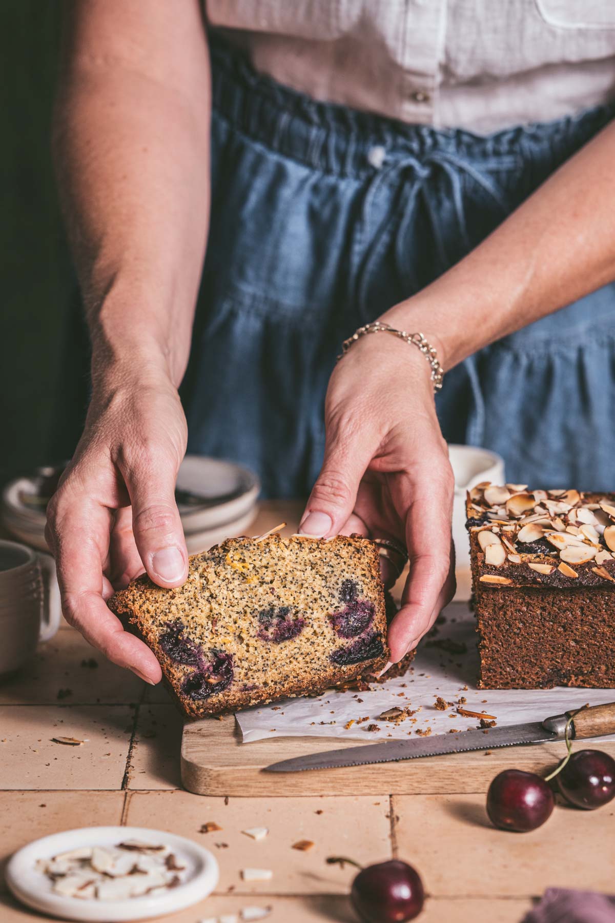 hands in frame holding a slice of cherry bread