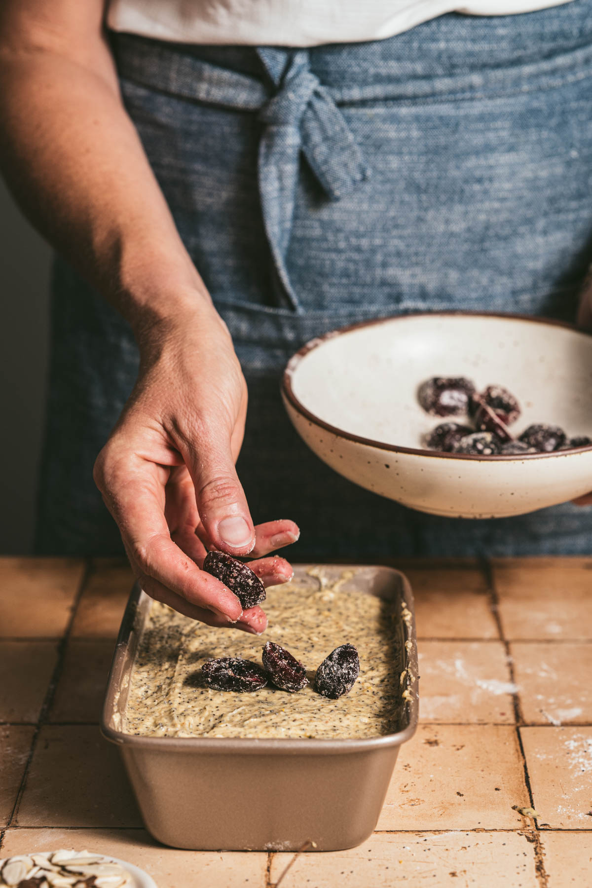hands in frame adding cherries on top of the batter