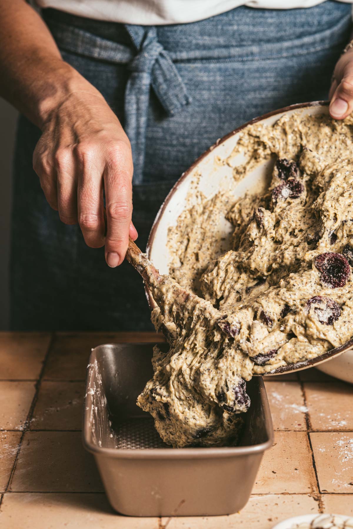 hands in frame adding batter to a baking pan