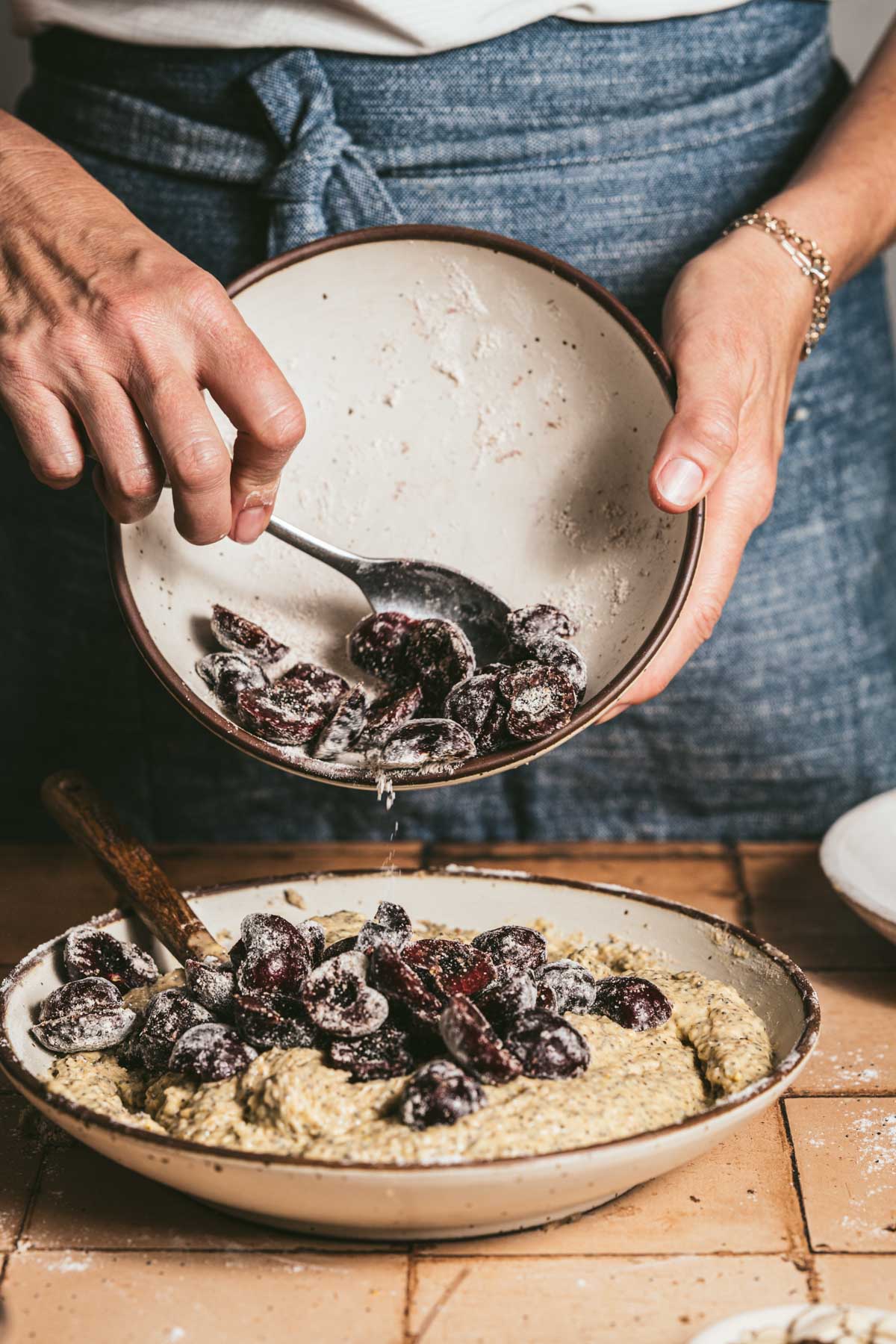 hands in frame adding cherries to batter