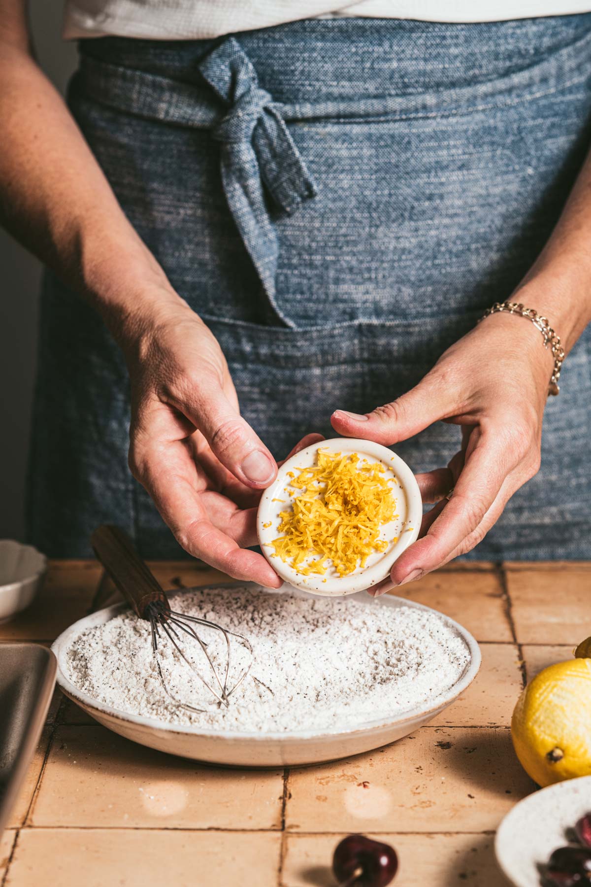 hands in frame adding lemon zest