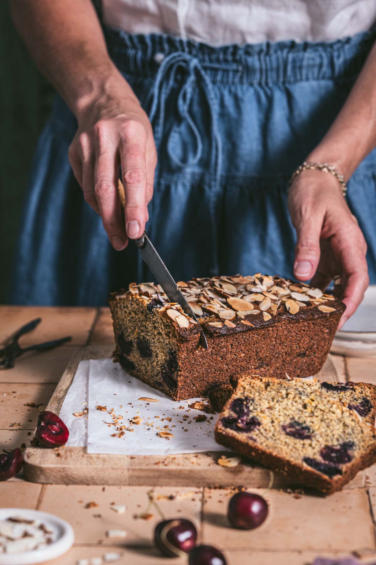 hands in frame holding knife and slicing cherry bread