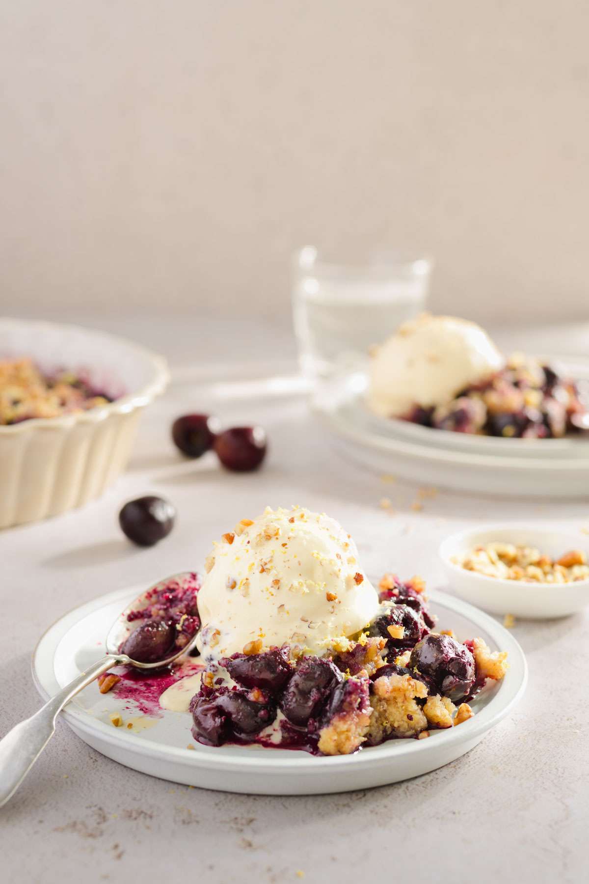 cherry crisp on a plate served with a scoop of ice-cream