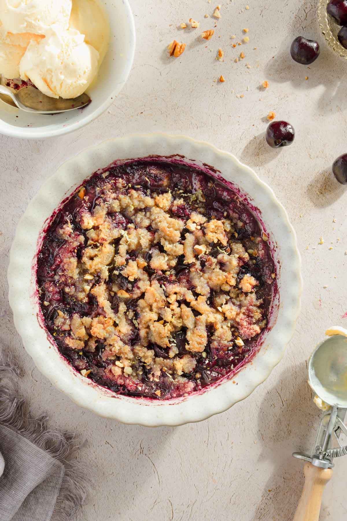 baked cherry crisp shown in a serving dish; light background