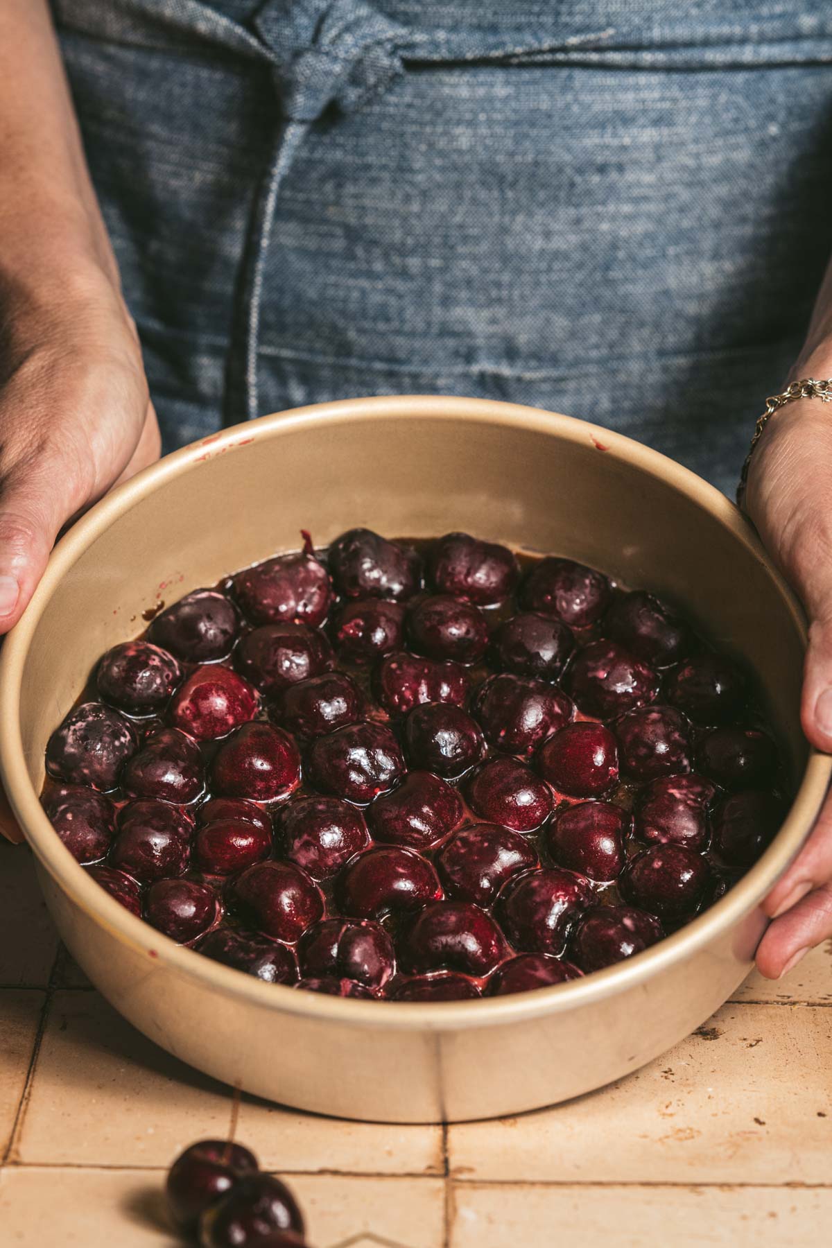 hands in frame holding pan with arranged cherries