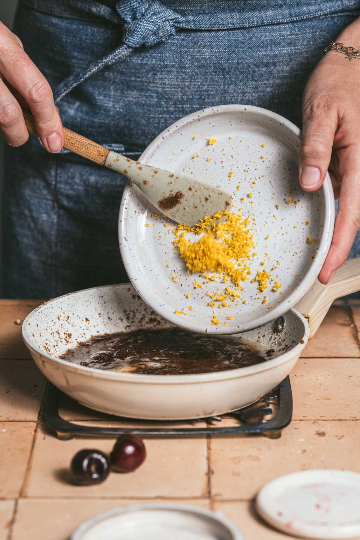 hands in frame scooping lemon zest into a pan