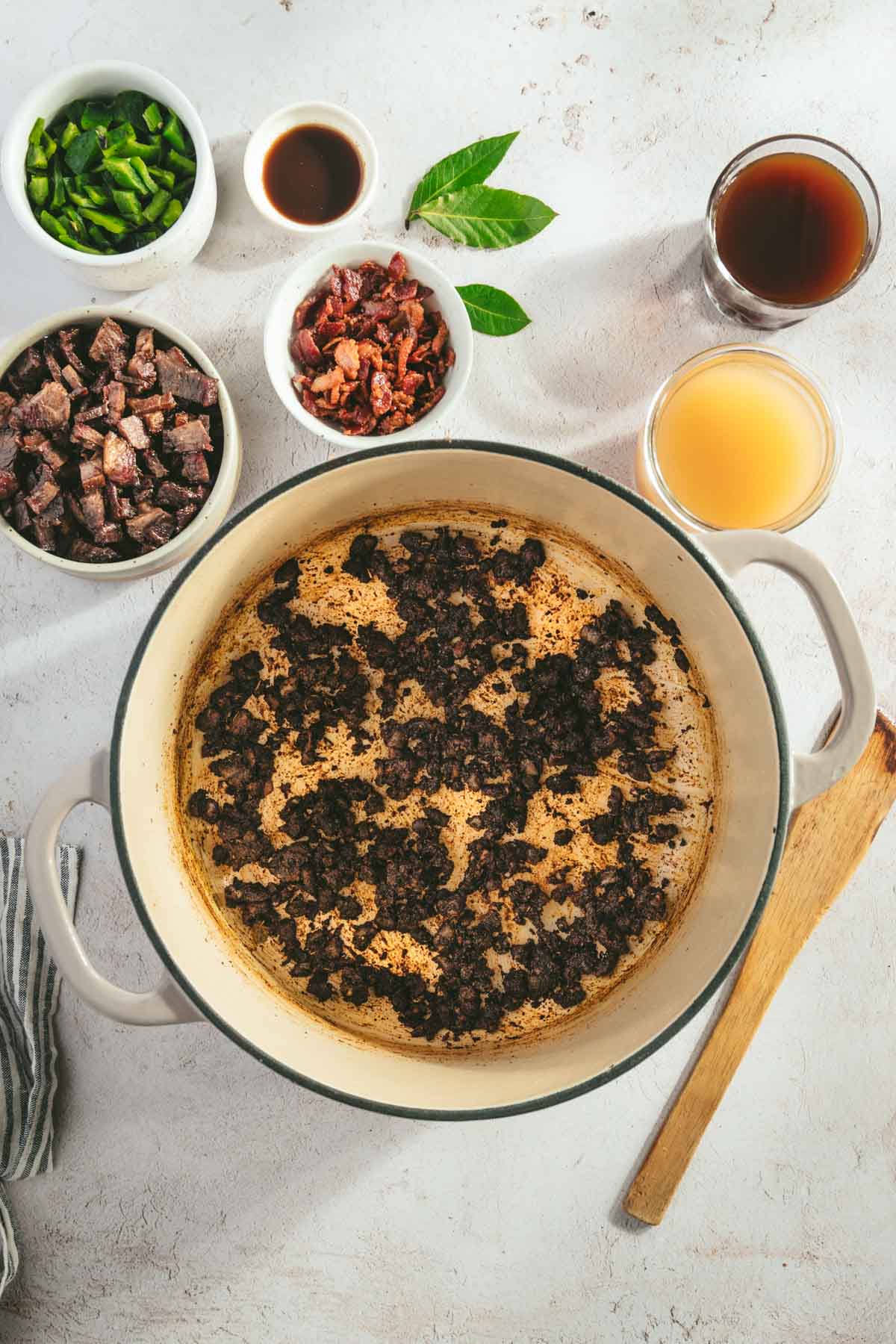 large cooking pot with cooked onions with spices, bowls with other ingredients around