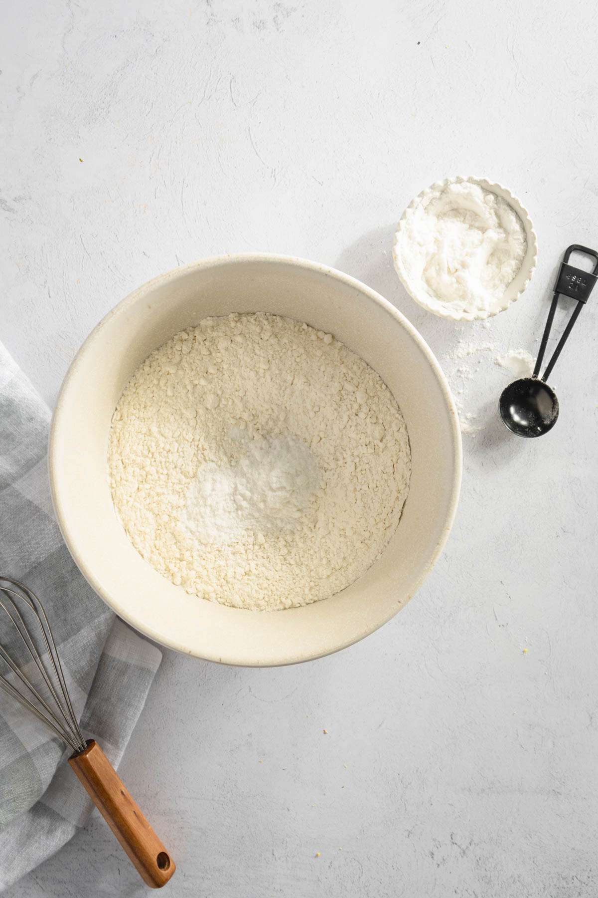 large bowl with flour, small bowl and measuring spoon on the side