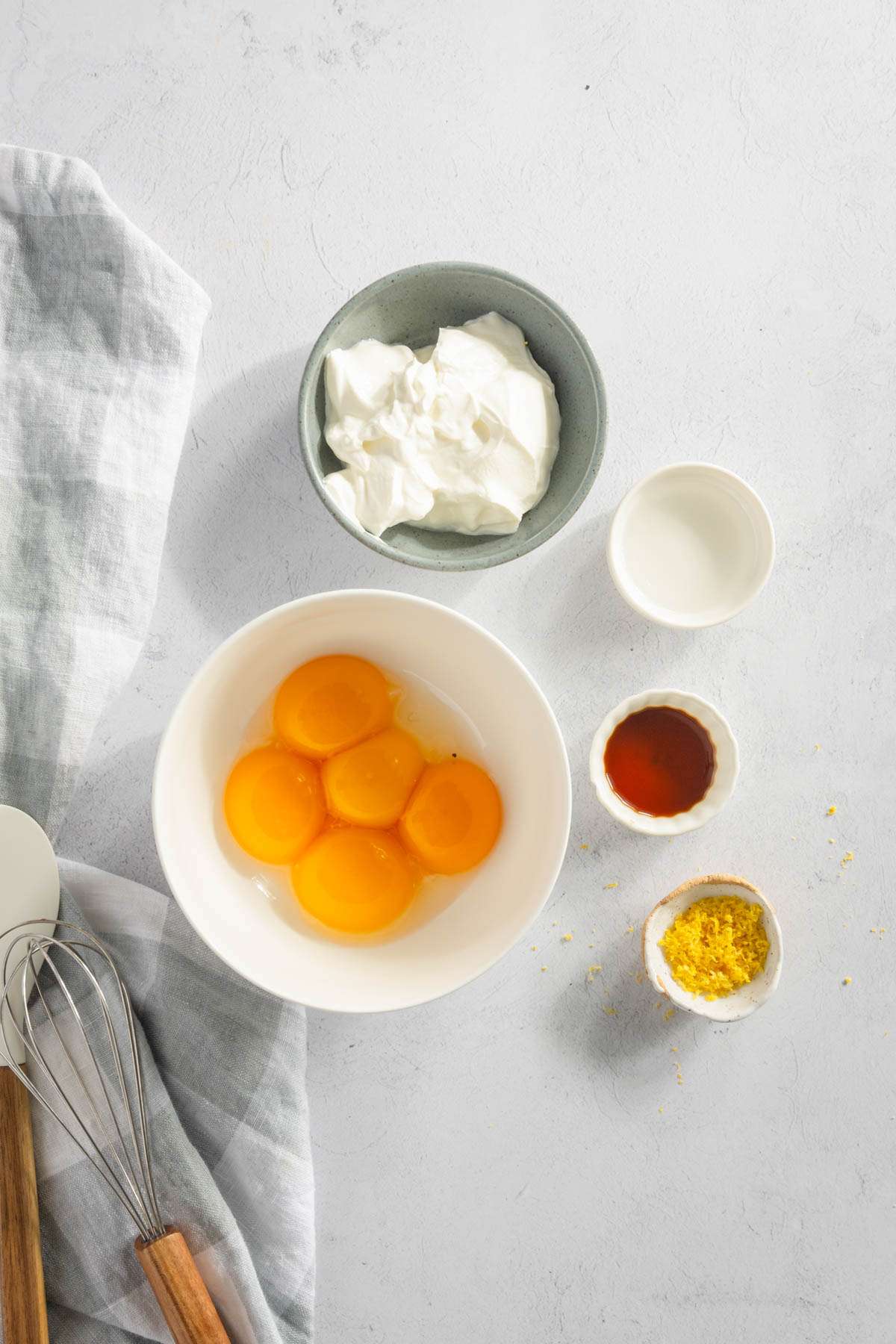 5 egg yolks in a small bowl, other ingredients for chrusciki in small bowls set around