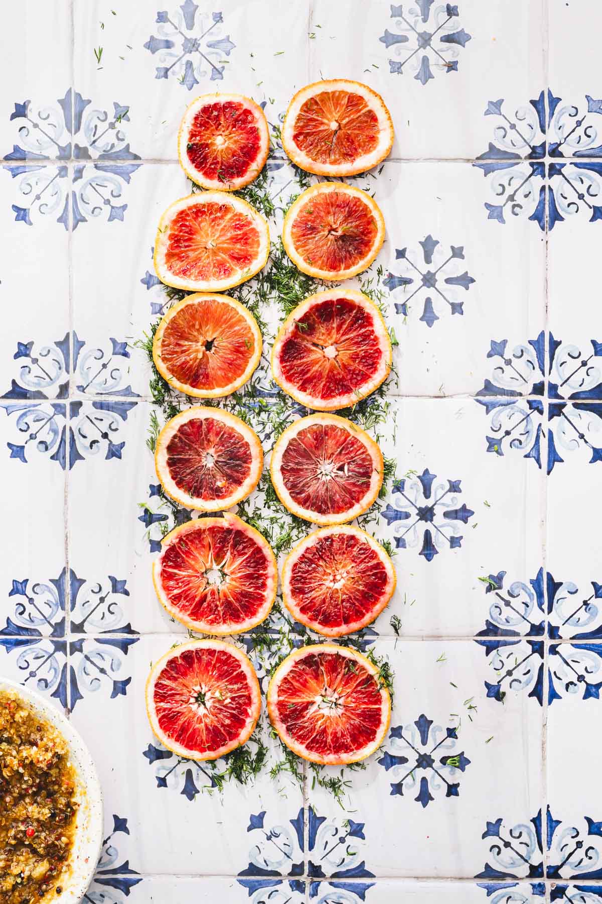 slices of orange lined up atop of chopped dill