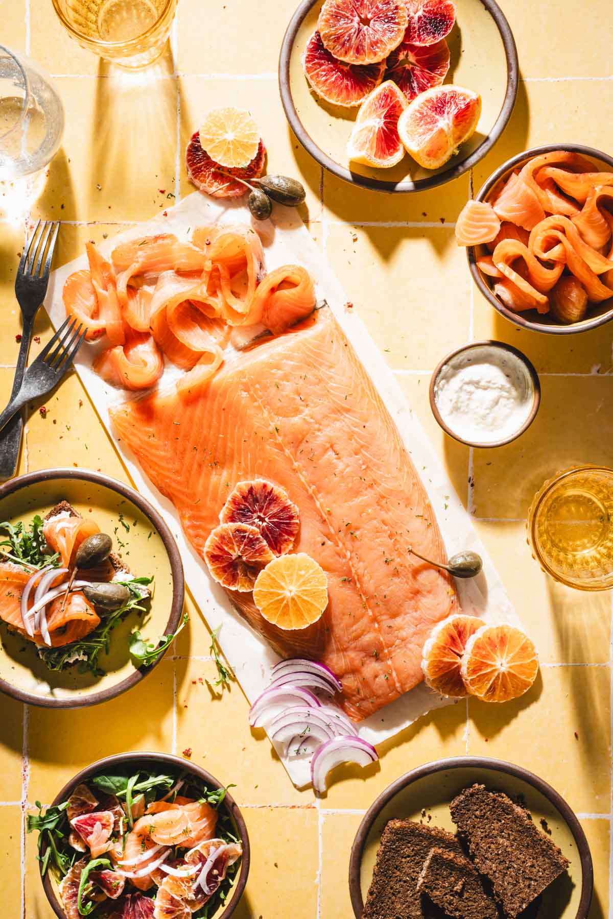 cured salmon on a parchment paper; various plates with slices of salmon, bowl with a salad