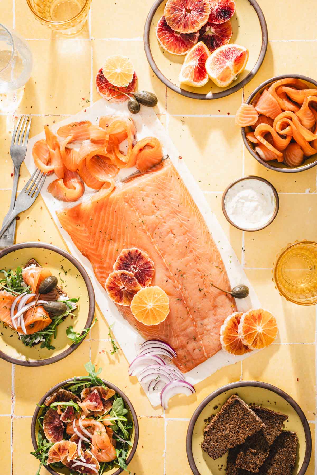 cured salmon on a prachment paper; various plates, bowls, glasses with water