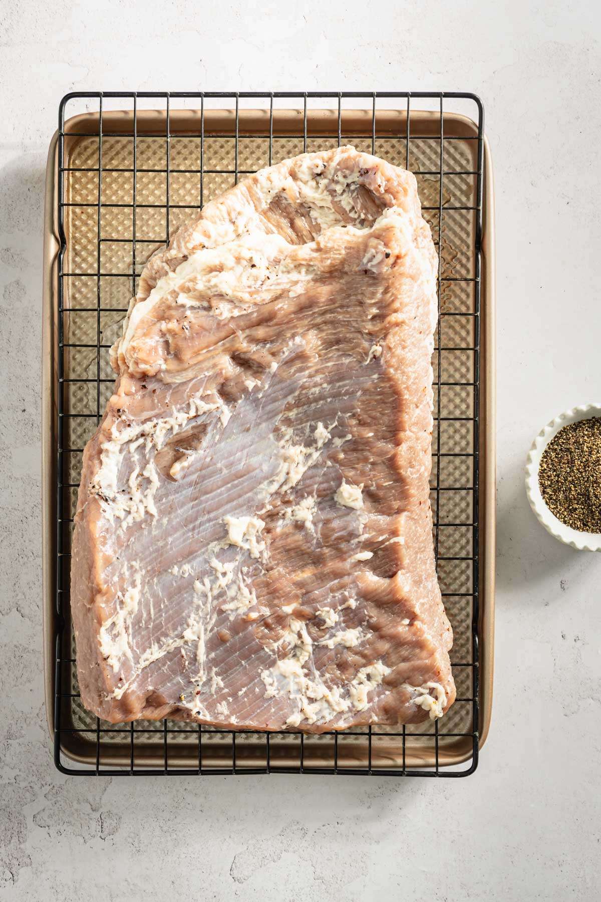 raw corned brisket on a drying rack, dish with black pepper