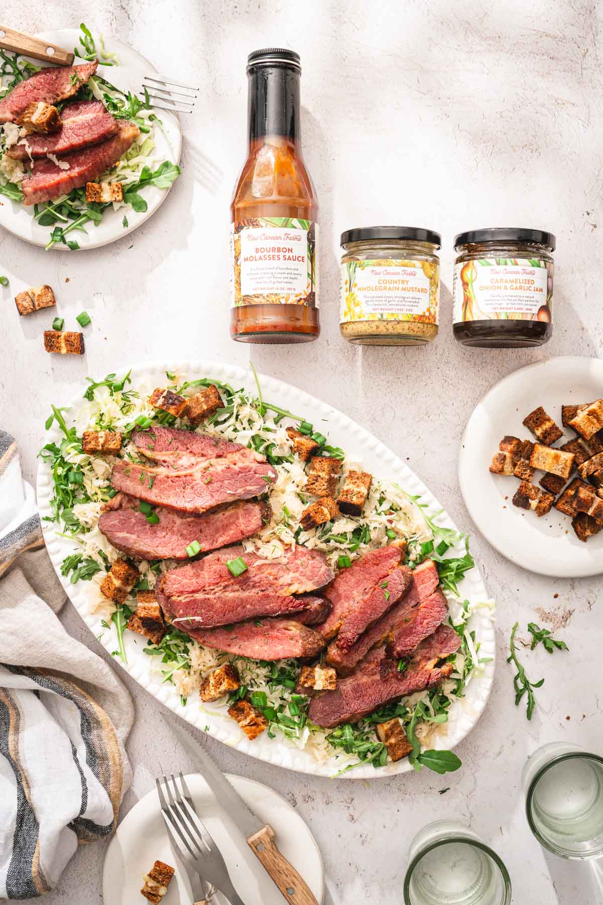 platter with the salad, two jars and a bottle with the products, other plates with the sald and croutons