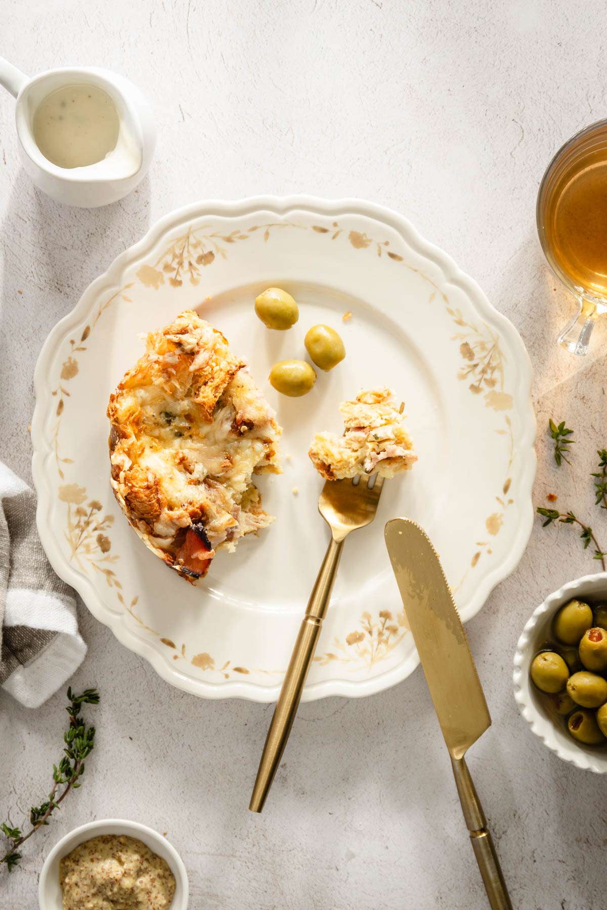 slice of croissant bake on a plate, dishes with olives, sauce