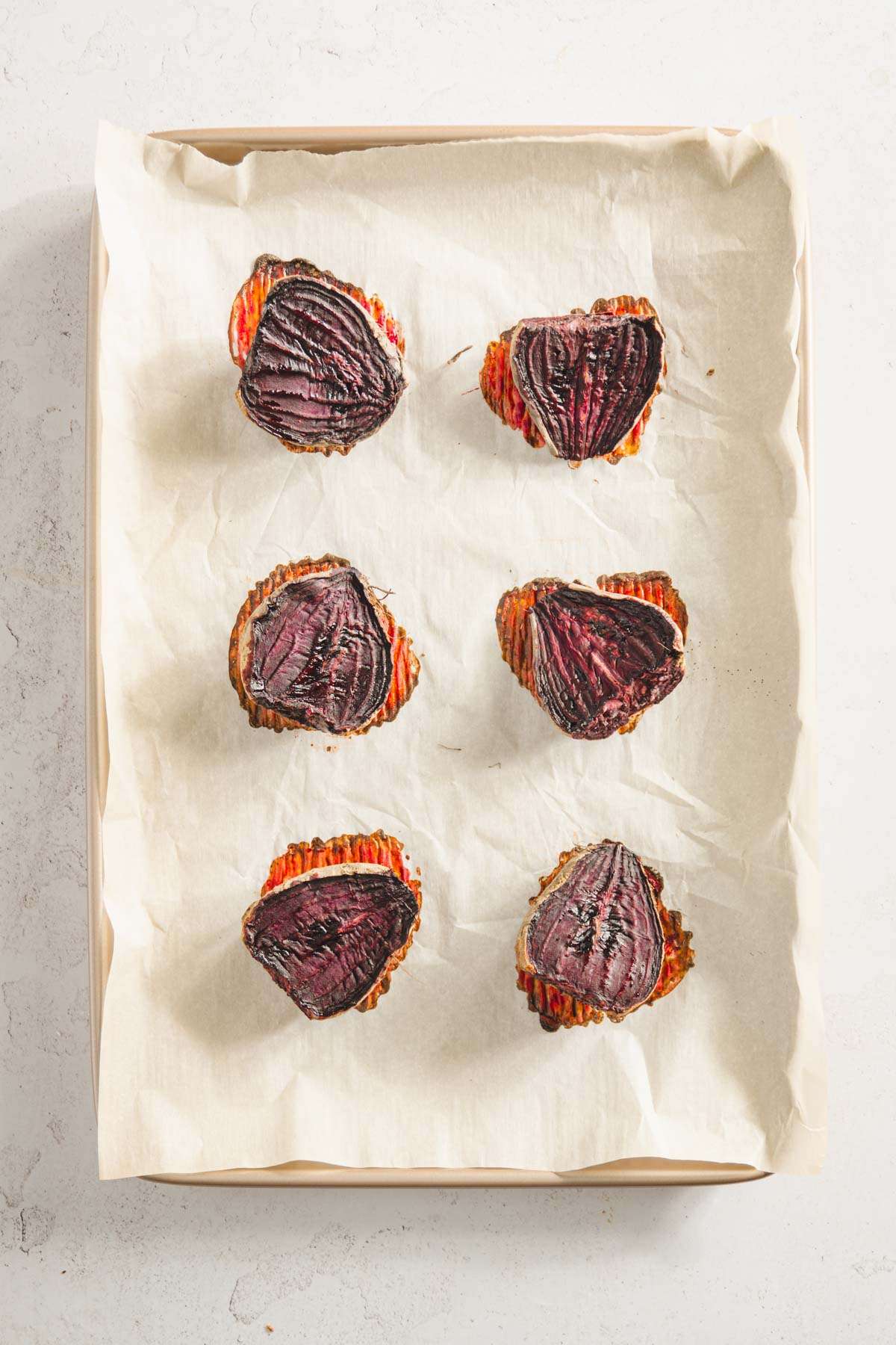 roasted and cut in half beets on a baking sheet