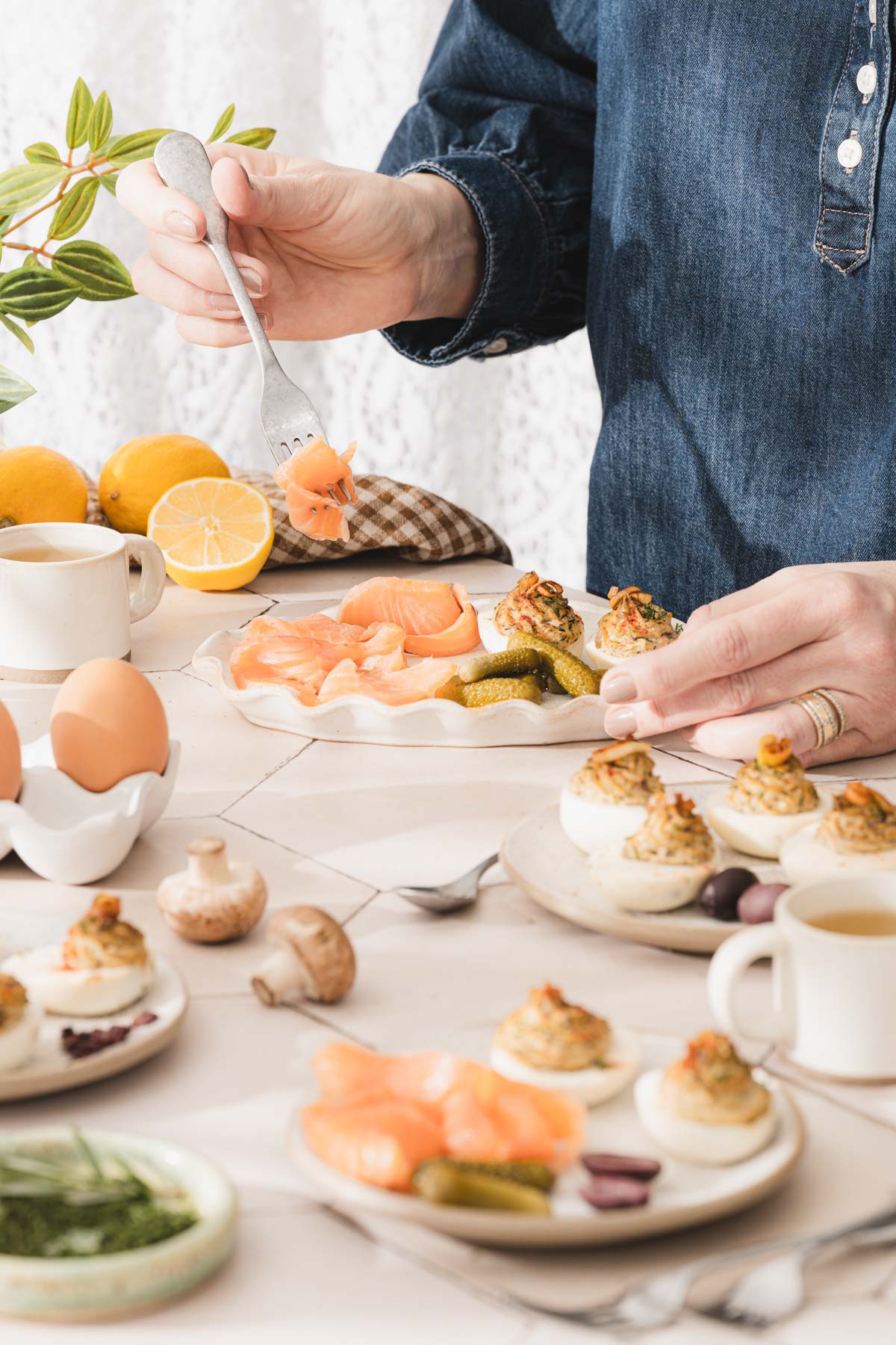 hands in frame over a plate with smoked salmon and deviled eggs