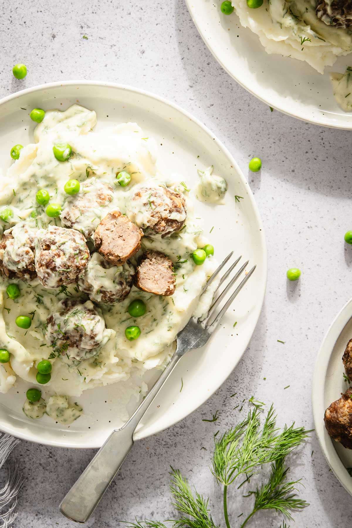 close up of a plate with dill meatballs over mashed potatoes