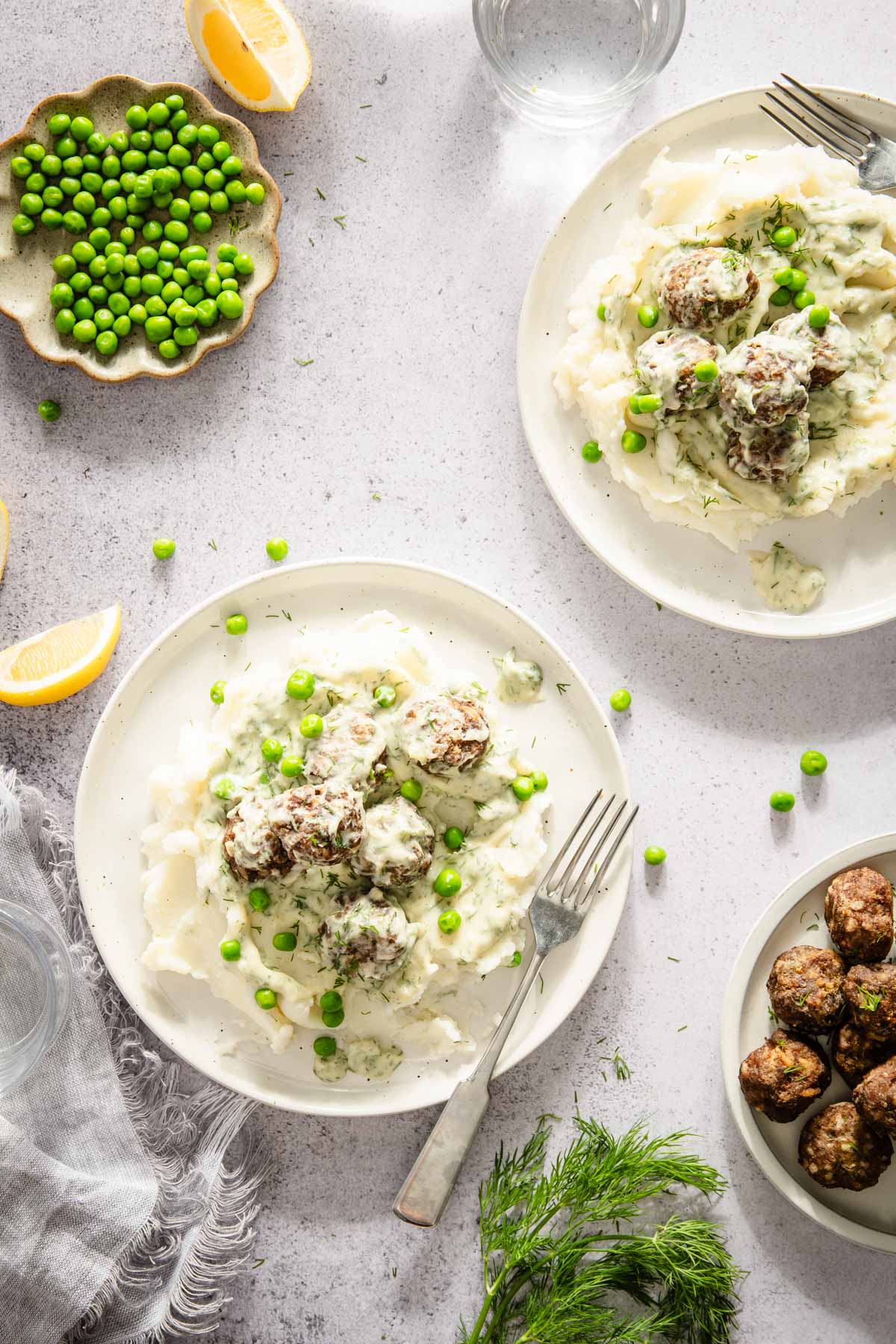 dill meatballs served over mashed potatoes, plate with just meatballs, dish with green peas