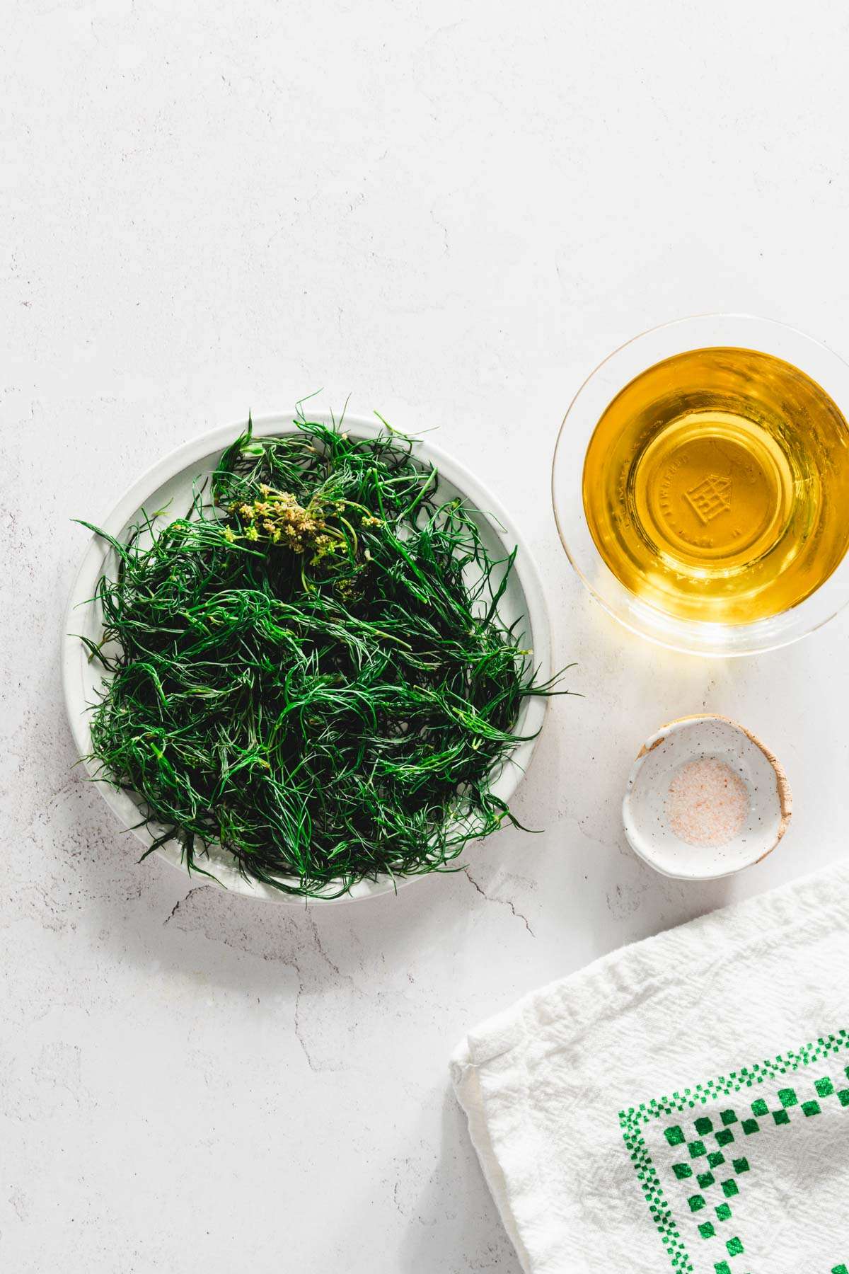 blanched dill on a plate, dish with oil and salt to the side