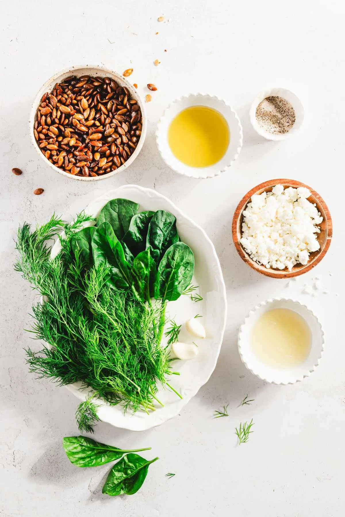 oval plate with spinach, dish with roasted pumpkin seeds and other ingredients to make the pesto