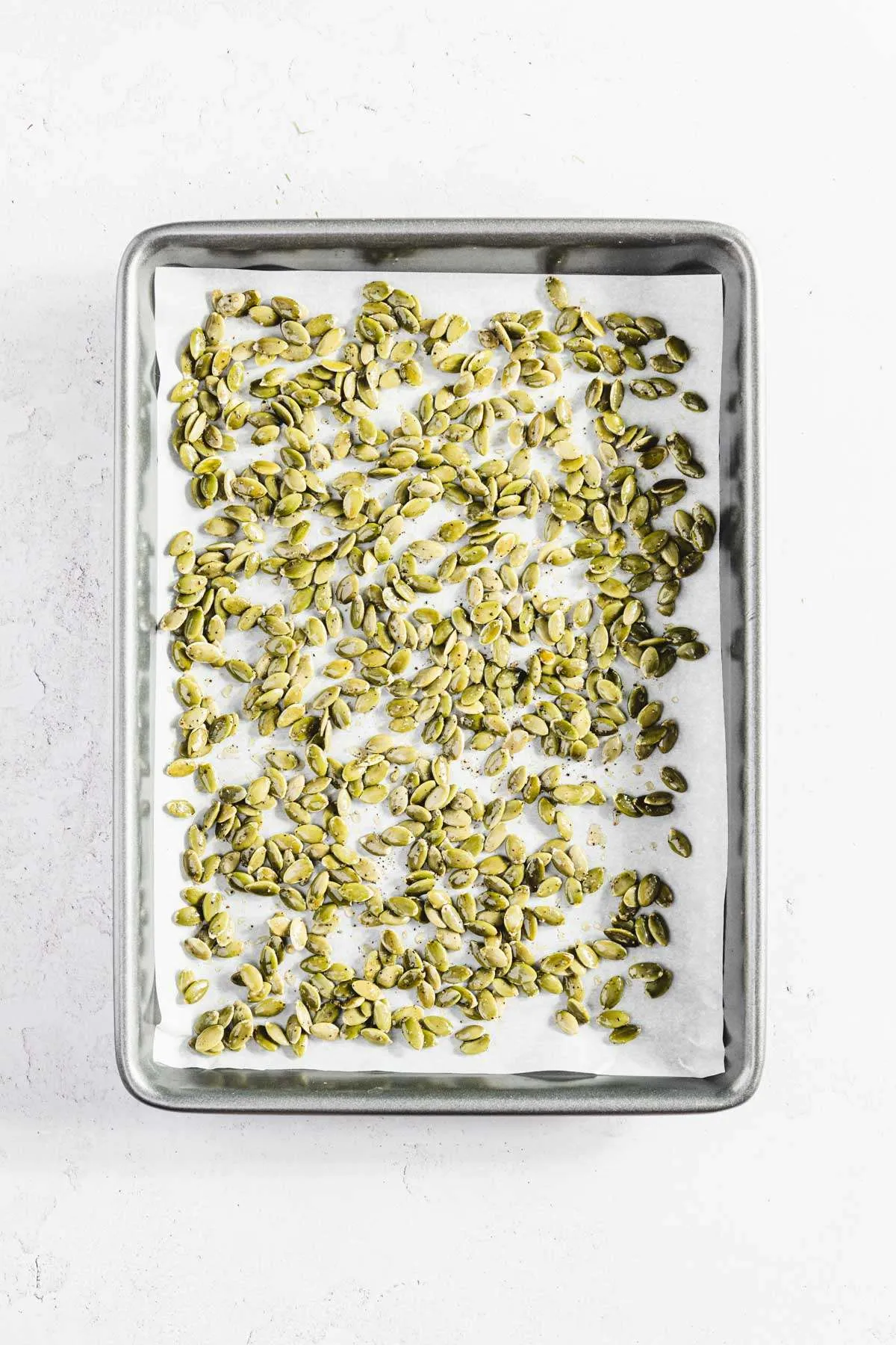 raw pumpkin seeds on a baking sheet