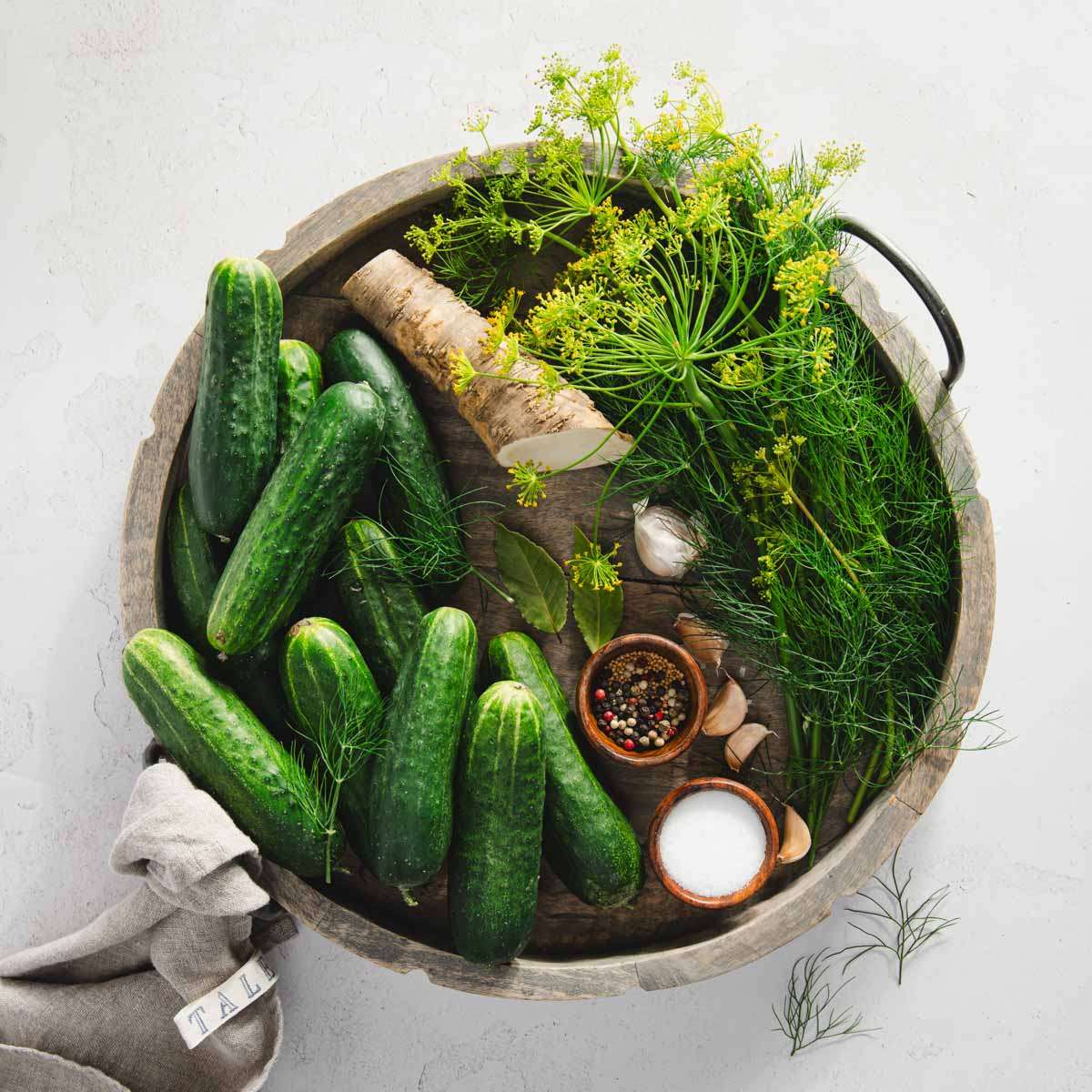 ingredients to make half sour pickles arranged on a wooden tray